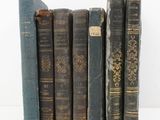 several old books are lined up in a row on a white surface