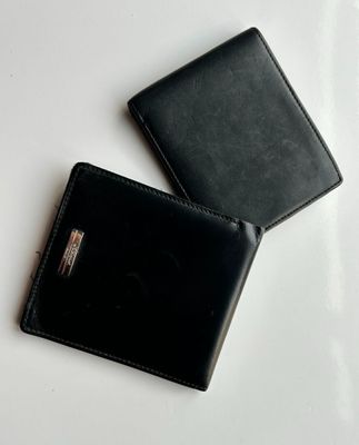 deux portefeuilles en cuir noir posés l'un à côté de l'autre sur une surface blanche