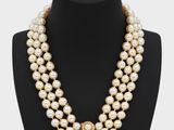 a three strand pearl necklace with a gold clasp on a mannequin