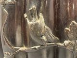 un vase en argent orné d'un oiseau