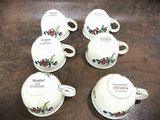 four tea cups and saucers sitting on top of a wooden table