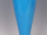 a blue vase sitting on a table with a gold rim