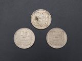 three silver coins sitting next to each other on a black surface