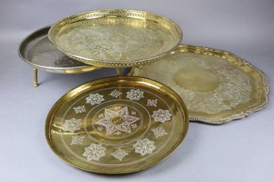 trois plateaux en argent et en or posés sur une table blanche