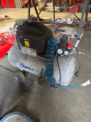a small air compressor sitting on the floor in a garage