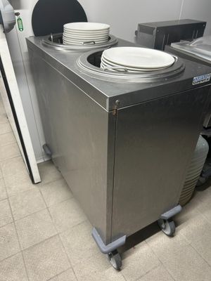 several plates are stacked on top of a metal box in a kitchen
