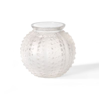 un vase en verre blanc muni d'un couvercle blanc, posé sur une surface blanche
