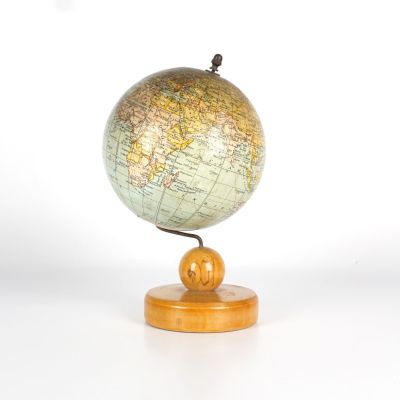 un petit globe posé sur un socle en bois, lui-même posé sur une surface blanche