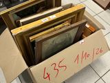 a cardboard box full of framed pictures on the floor