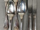 five forks, a spoon, and a knife on a table