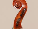 an antique violin with a scroll and a bow on a stand