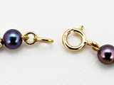 a close up of a purple pearl bracelet with a gold clasp