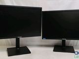 two computer monitors sitting side by side on a white surface