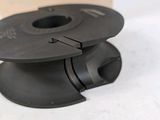 a spool of black plastic on a white surface