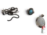 three pieces of jewelry on a white surface including a pendant, a ring, and a chain