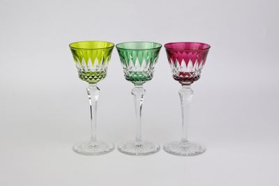 three different colored wine glasses sitting next to each other on a white surface