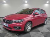 une voiture rouge est garée dans une pièce au sol en damier