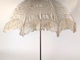 un parapluie en dentelle posé sur un support, devant un fond blanc