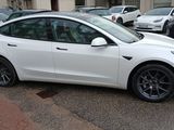 a white tesla model 3 parked in a parking lot