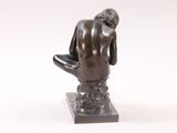 statue of a man sitting on a stool with his back to the camera