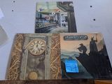 three books on a table with a clock on it