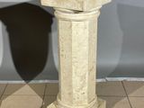 a marble pedestal on the floor with a shadow of a chair in the background
