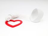 a red heart shaped object next to a white cup