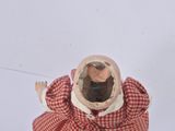 a small doll that is wearing a red and white checkered coat