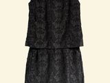 a black dress hanging on a hanger on a white wall