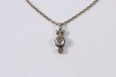 a close up of a necklace with a small owl on it