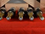 several bottles of wine sit in a wooden crate on a red cloth