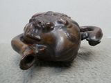 une statue représentant une grenouille assise par terre