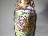 a vase with a painting on it sitting on a table