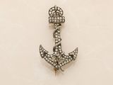 an anchor shaped broochle with diamonds on a white background