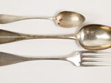 three spoons and a fork on a white surface