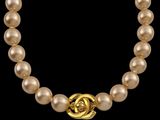 un gros plan sur un collier de perles muni d'un fermoir en or