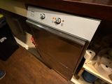 une personne debout devant un lave-vaisselle dans une cuisine