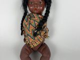 une image représentant une poupée représentant une petite fille aux cheveux noirs tressés