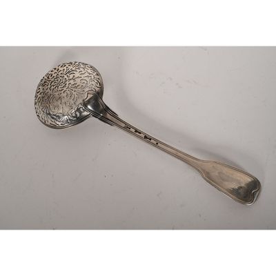 une cuillère ancienne en argent posée sur une surface blanche, avec un manche en argent