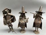three metal figurines of a man and woman playing instruments