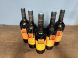 six bottles of wine are lined up on a wooden table