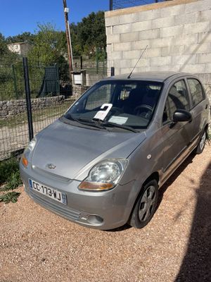 a small silver car parked in front of a brick wall