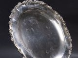 an antique silver plate on a stand against a black background