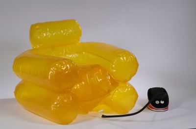 une chaise jaune fabriquée à partir de bouteilles en plastique, posée sur une surface blanche