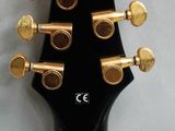 the headstock of an electric guitar with a black body and gold knobs