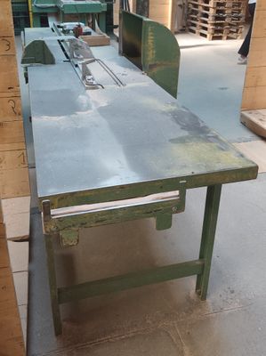 une table sur laquelle est posée une scie, au milieu d'une pièce