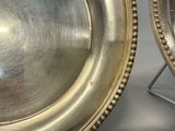 two silver plates sitting next to each other on a table