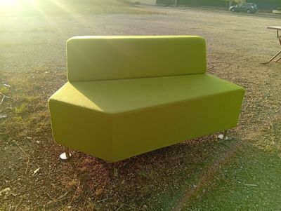 a green couch sitting in the middle of a field