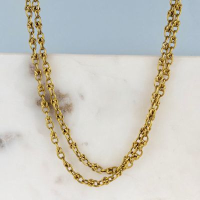 une photo d'un collier à chaîne en or posé sur une surface en marbre