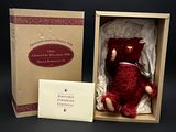 un ours en peluche rouge dans une boîte contenant une carte